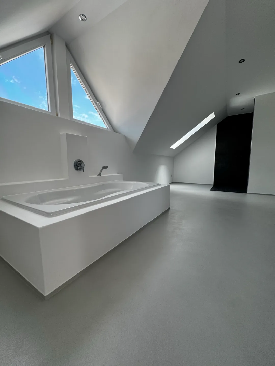 Dachbadezimmer mit fugenlosen Wand- und Bodenflächen und freistehender Wanne – Malerbetrieb Mergenthaler im Saarland